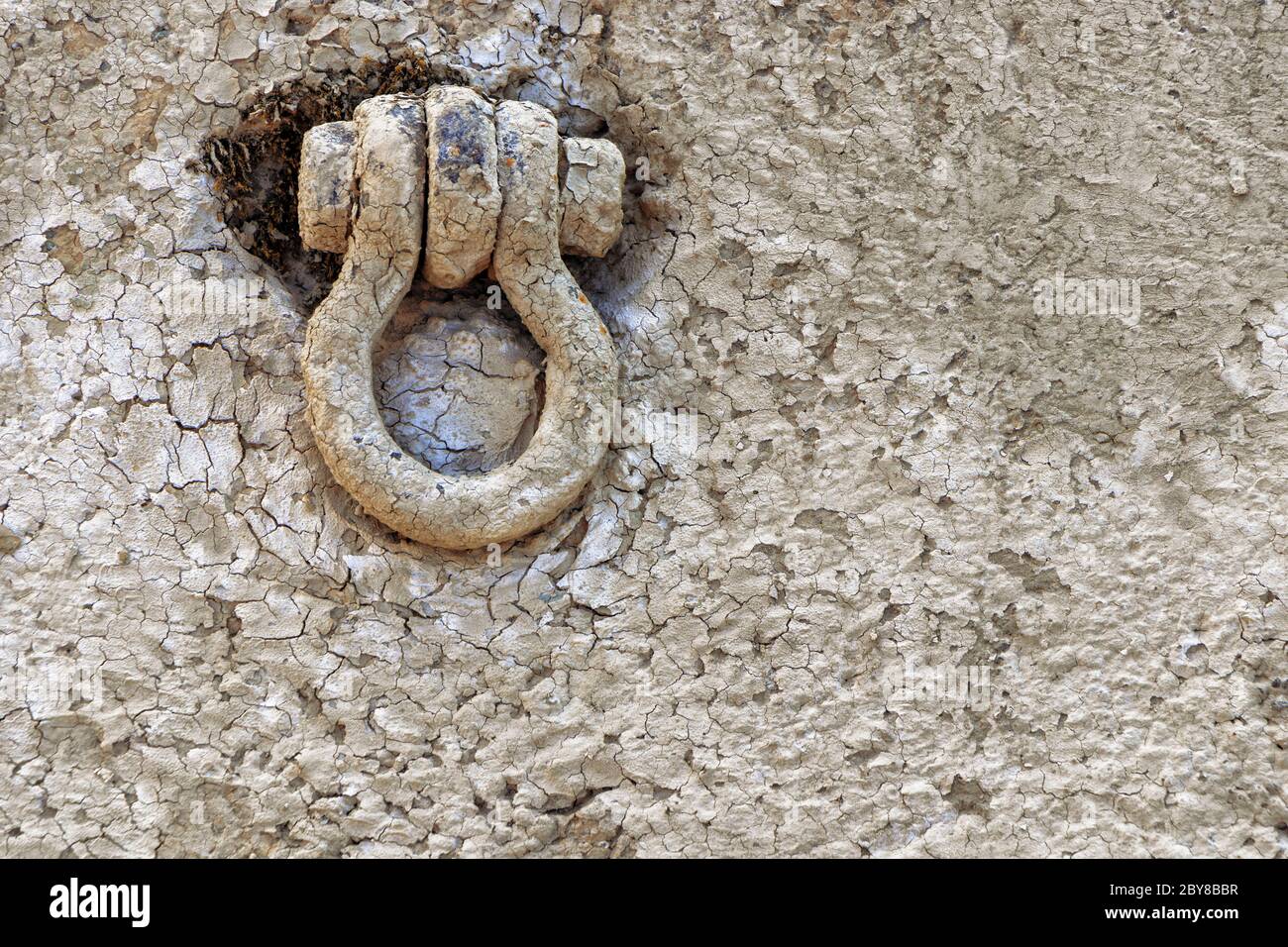 Weathered, mud covered iron eyelet to fasten ships with steel rope Stock Photo