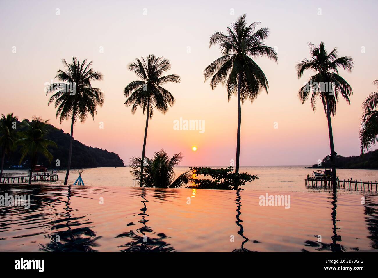 Sunset reflecting on the water surface foreground with coconut trees area ao bang bao at Koh kood island is a district of Trat Province. Thailand. Stock Photo