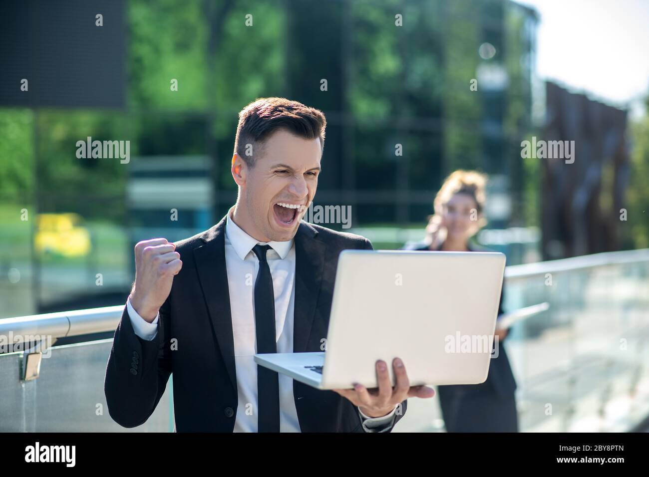 Young man with a laptop enthusiastically rejoicing Stock Photo