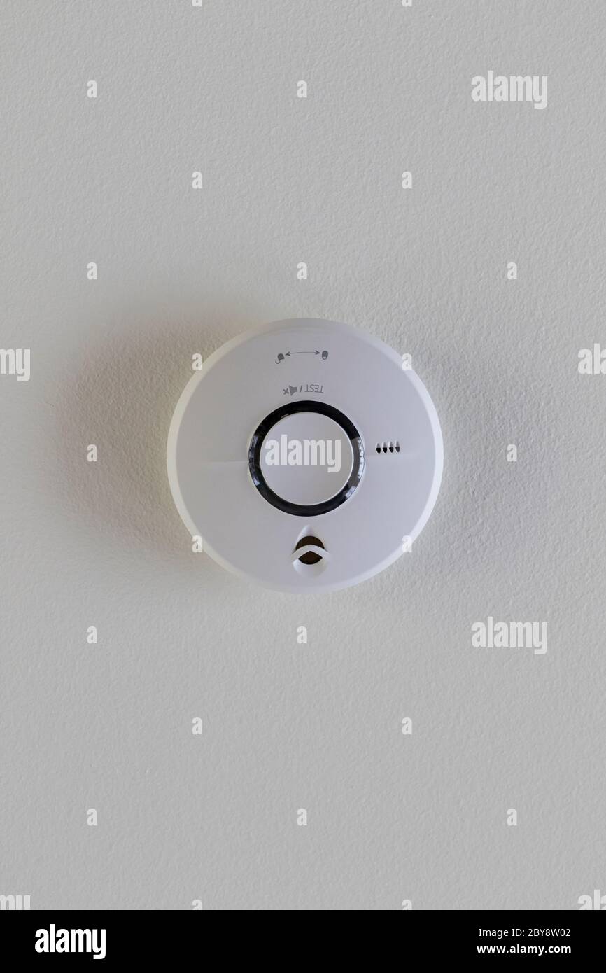 A close up portrait of a smoke detector sticking on a ceiling for
