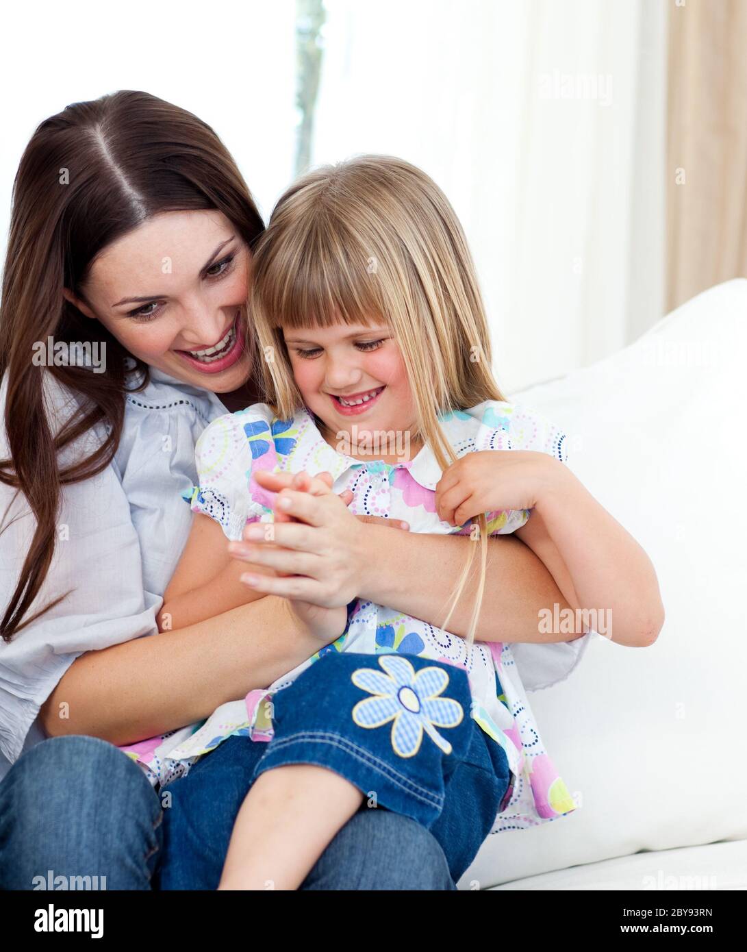 Cute girl sitting on her mother's lap celebrating a goal Stock Photo