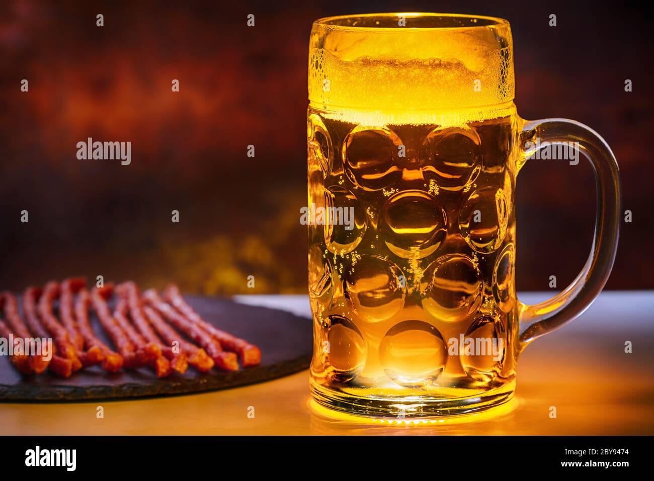 Tankard of ice cold beer served with dried spicy sausage snacks on a platter in a pub in a close up side view Stock Photo