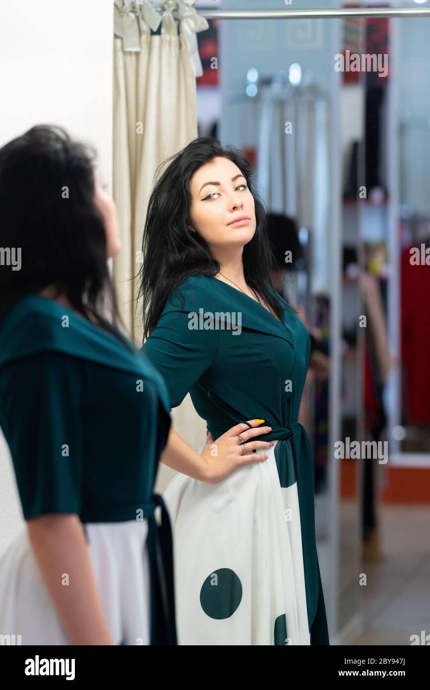 Attractive woman trying on clothes in a boutique store assessing a new