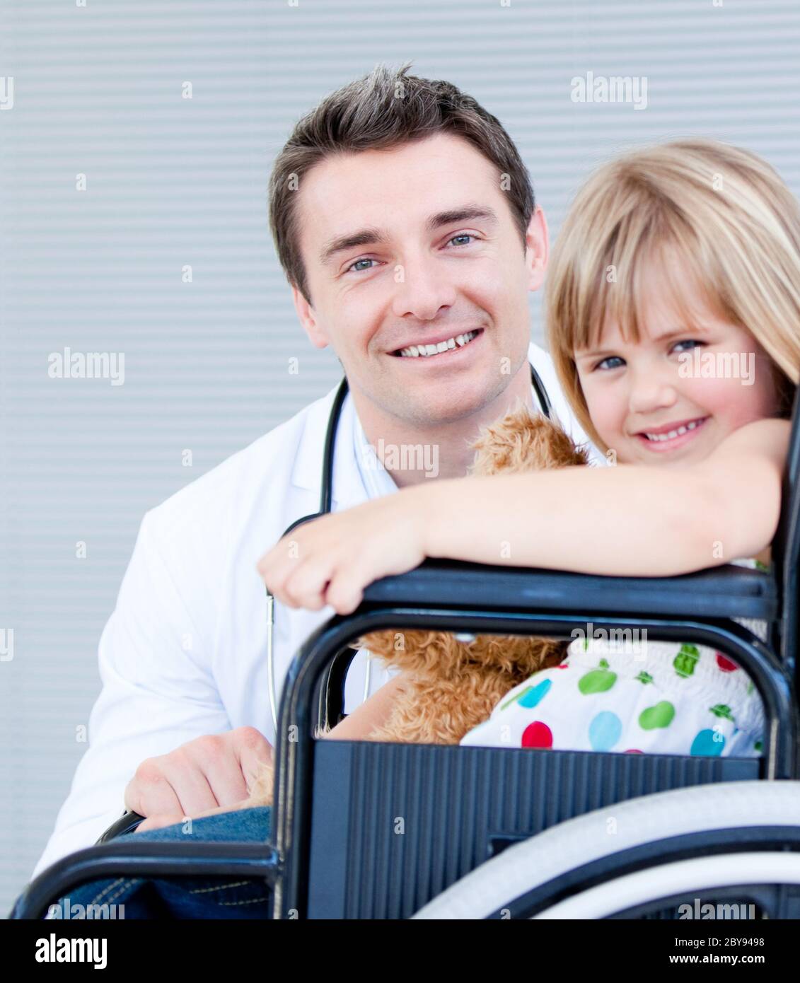 Cute little girl sitting on a wheelchair with her doctor Stock Photo