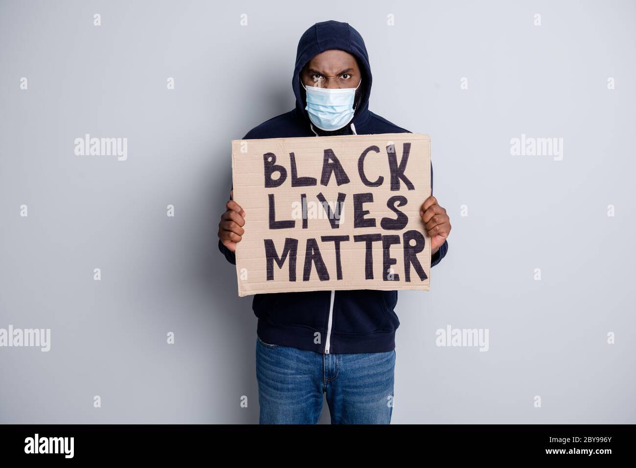 Save black lives. Photo of mad dark skin african poor covid infected protester hold placard stand against black citizens lawlessness wear hoodie face Stock Photo