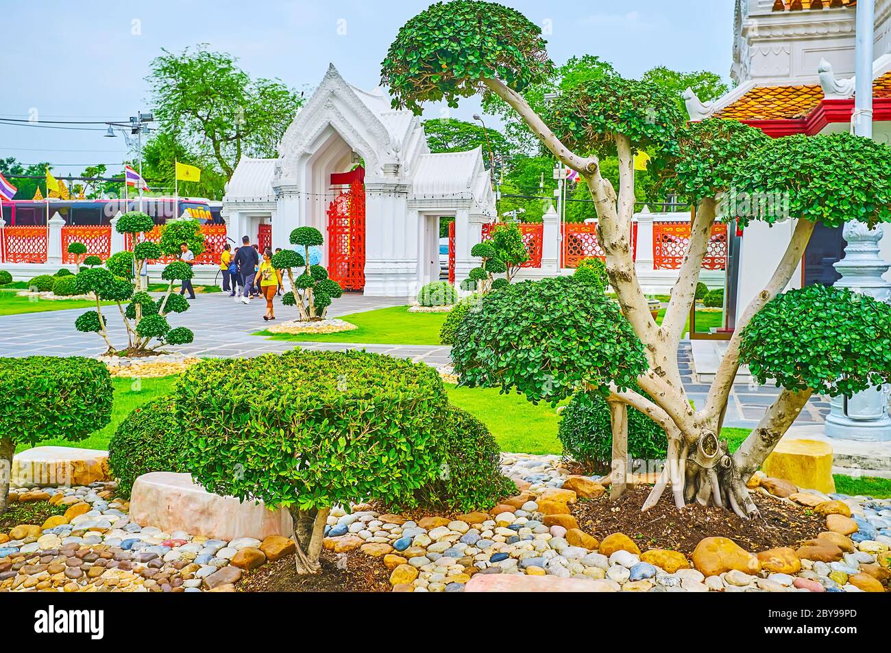 BANGKOK, THAILAND - MAY 13, 2019: Enjoy the topiary garden of Wat Benchamabophit Dusitvanaram Marble Temple with its carved white gate on the backgrou Stock Photo