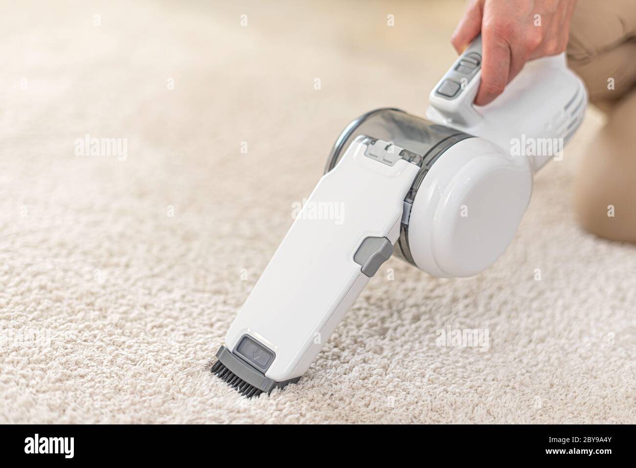 Woman vacuuming furniture in a house with a handheld portable vacuum cleaner Stock Photo Alamy