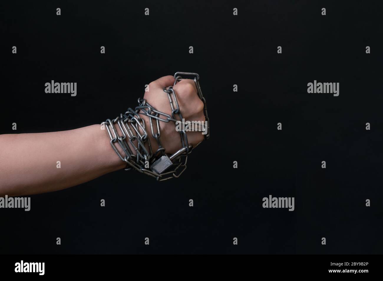 Fist of Hand are chained in chain on the black background, concept of