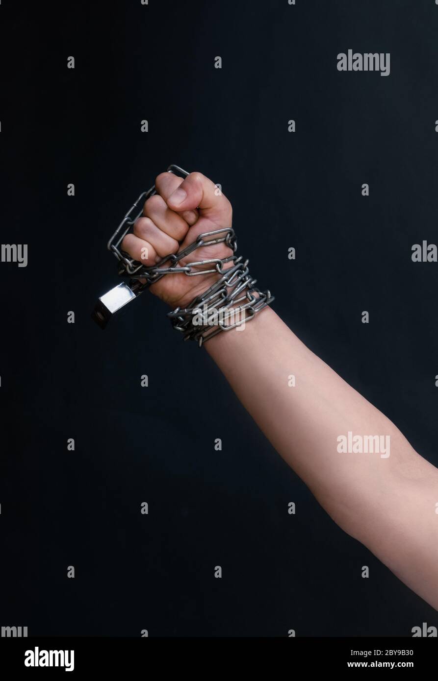 Fist of Hand are chained in chain on the black background, concept of