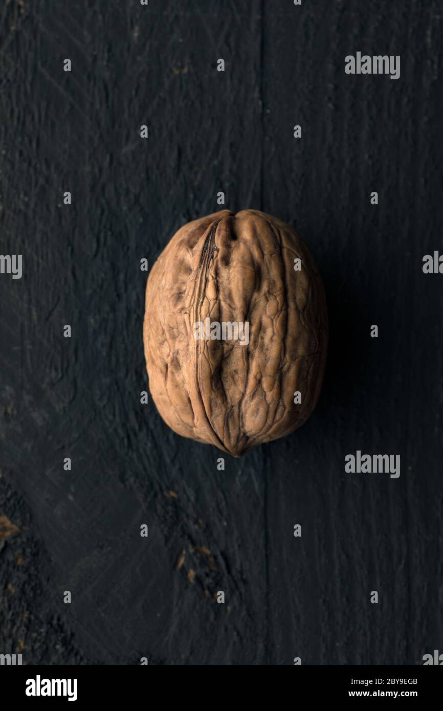 One Walnut on a Black Wooden Surface Stock Photo