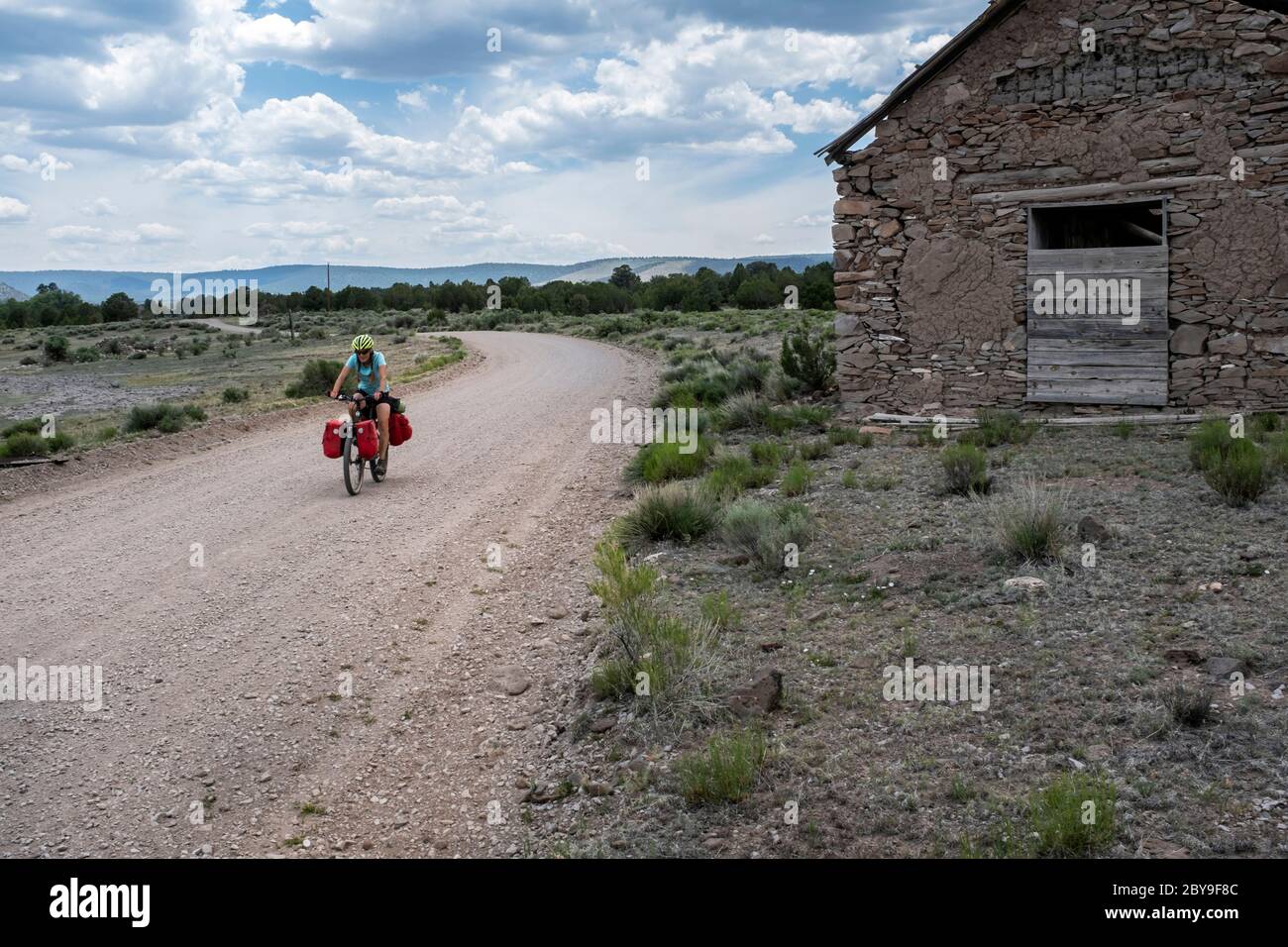 NM00127-00...NEW MEXICO - Vicky Spring ridding the Great Divide Mountain Bike Route passes by a slab and mortar church along Forest Road 214. Stock Photo