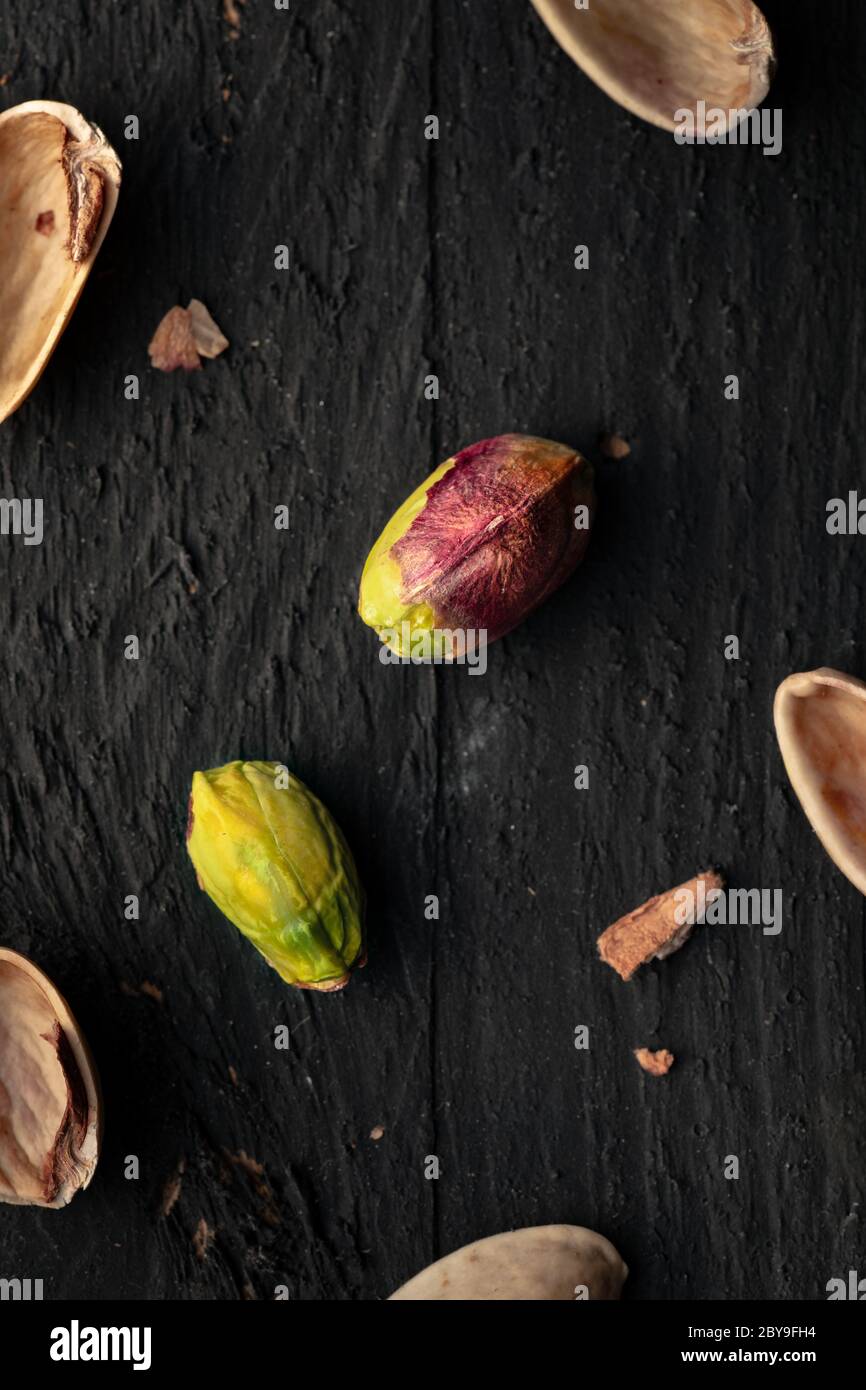 Pistachio on a Black Wooden Surface with Scattered Nutshell Pieces Stock Photo