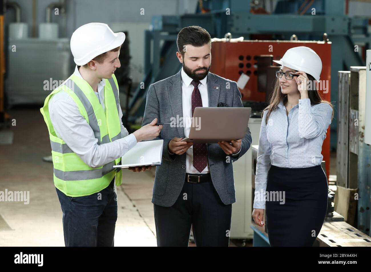 Portrait of a solid businessman with his secretary and factory engineer ...