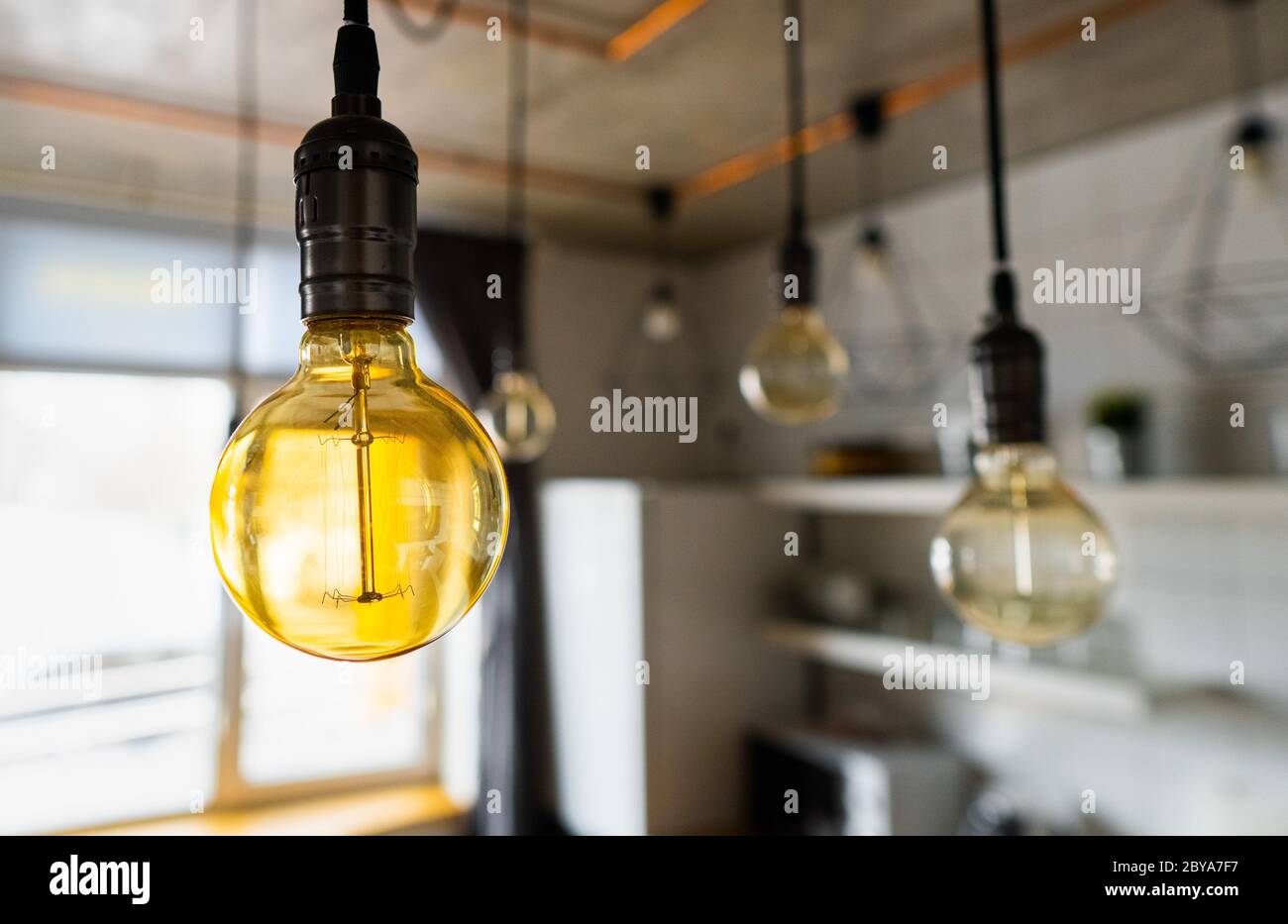 Big vintage incandescent light bulbs hanging in modern kitchen