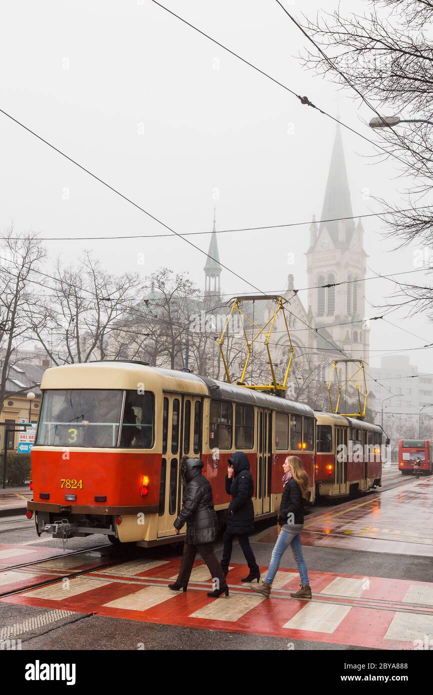 Women cross the road behind a tram in Bratislava, Slovakia in Febuary 2015. Stock Photo