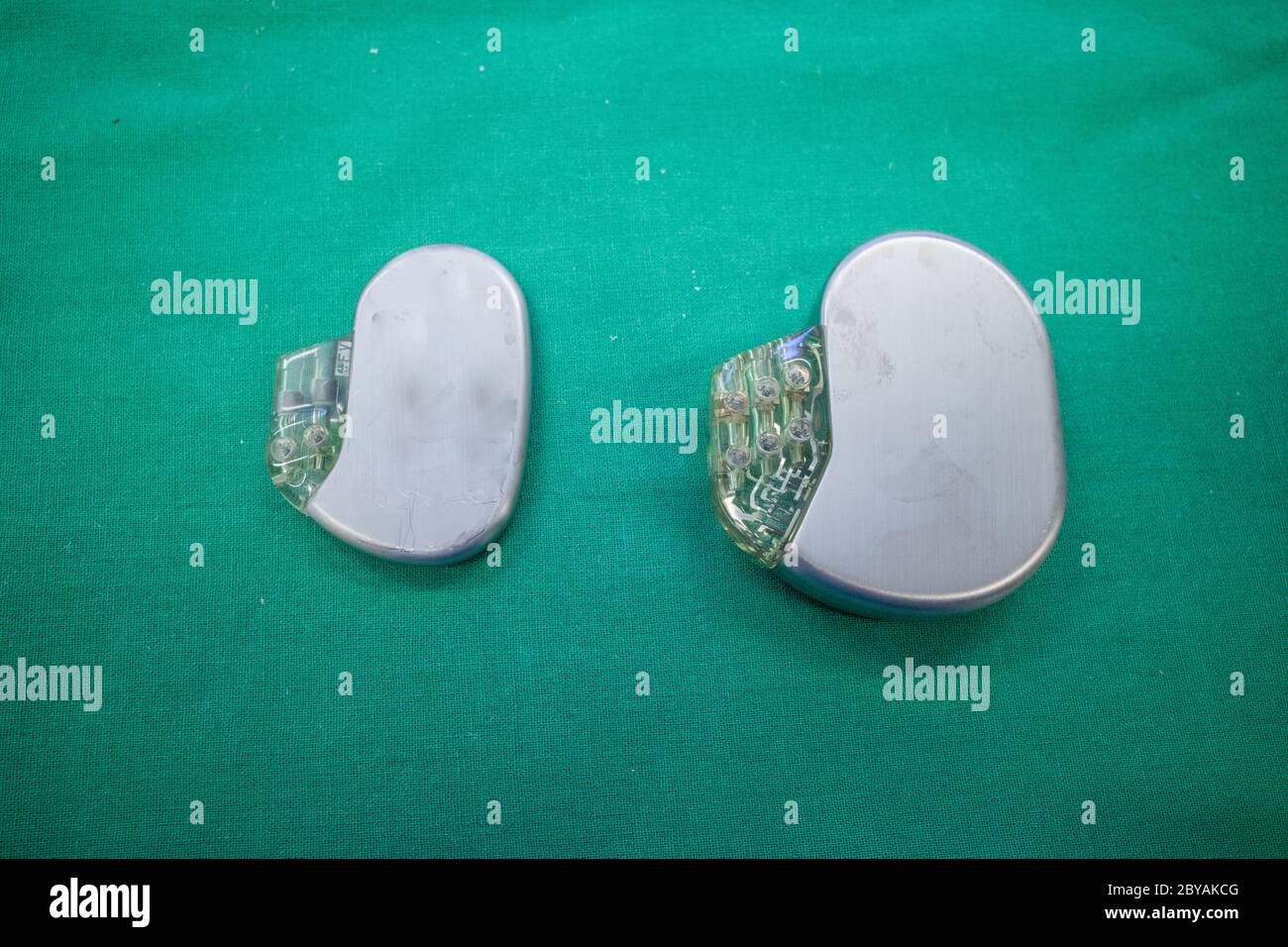 a pacemaker lies directly next to a defibrillator on a green surgical ...