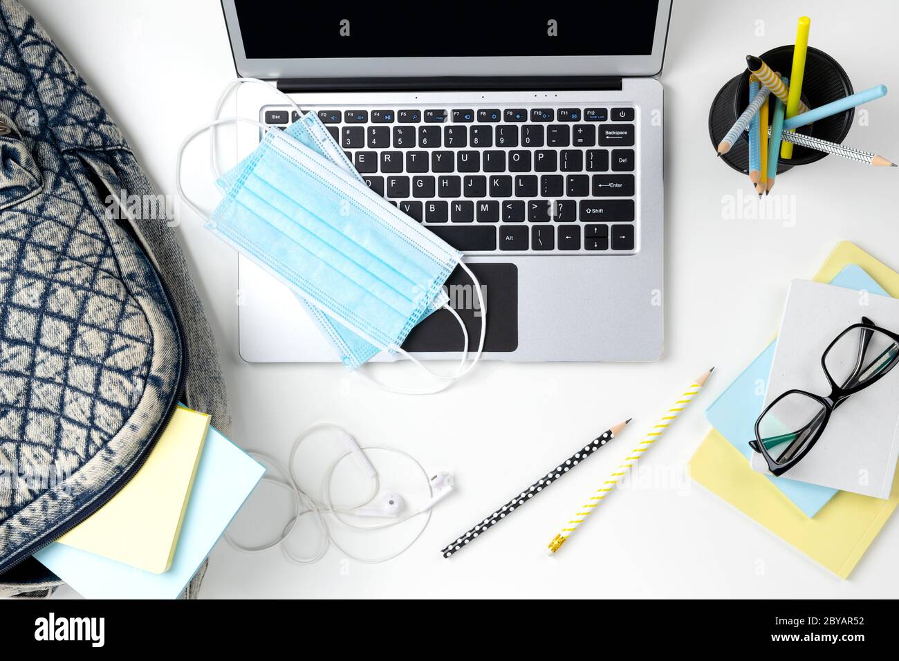 Modern laptop with backpack and stationery on white table Stock Photo