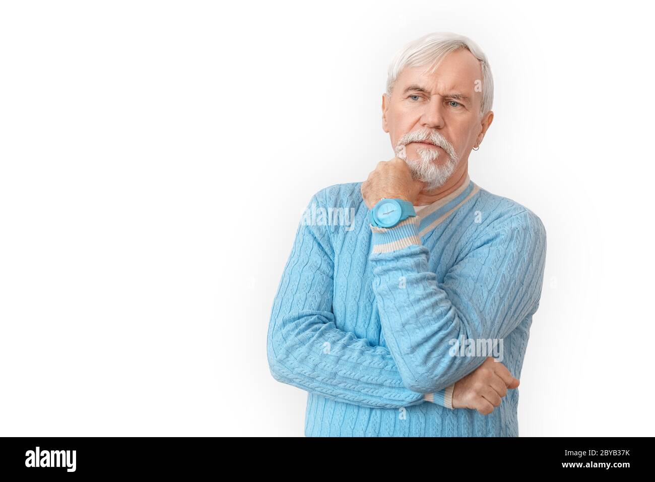 Freestyle. Senior bearded man in sweater standing isolated on white touching chin pensive Stock Photo