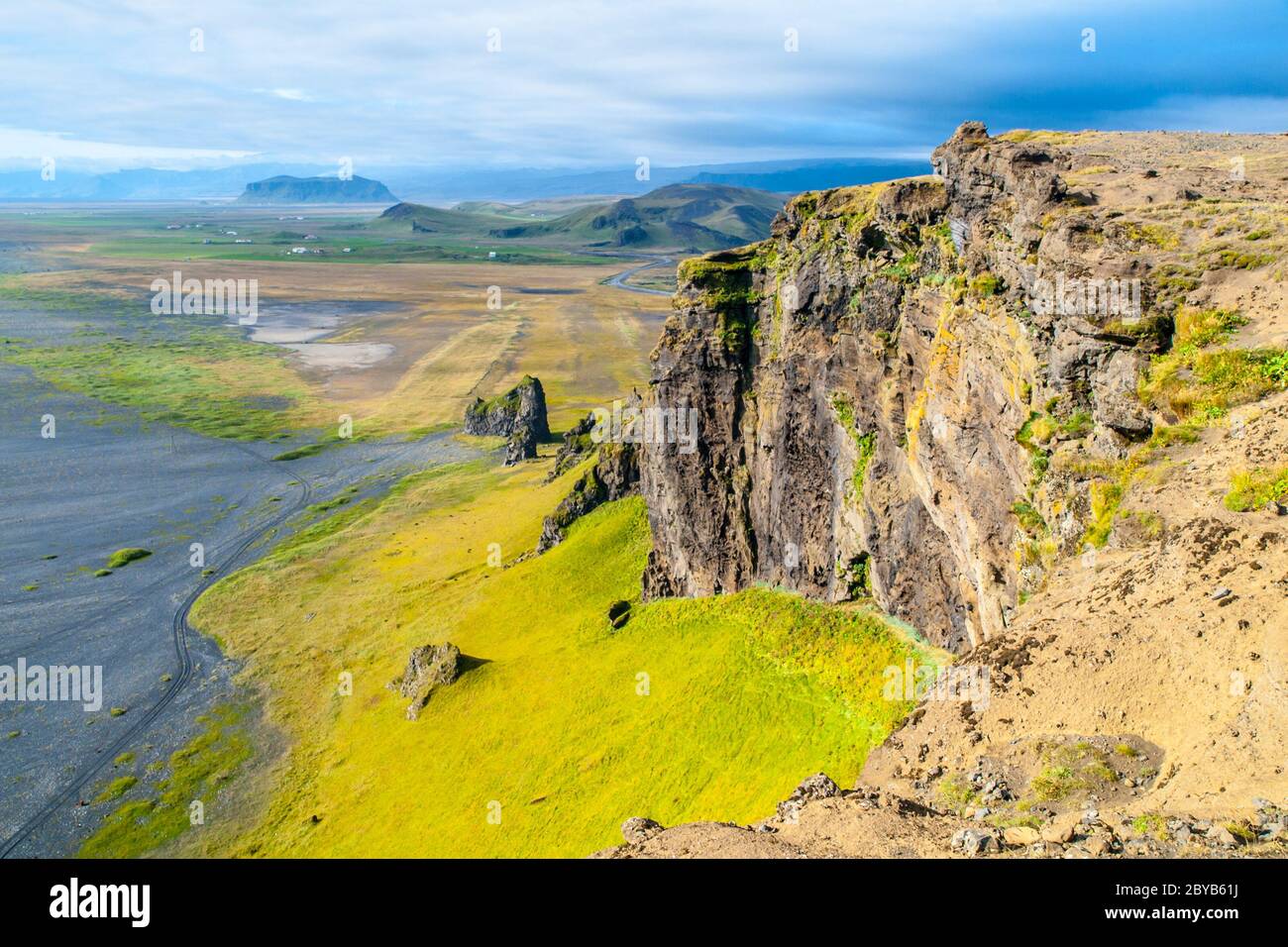 Dramatic rocky coastline landscape with green steep slopes, wild rocks and black beach, Iceland. Stock Photo
