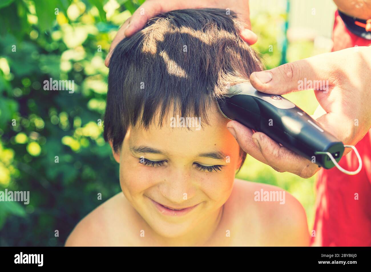 Hand Holds An Electric Hair Clipper And Cuts The Boy s Long Hair