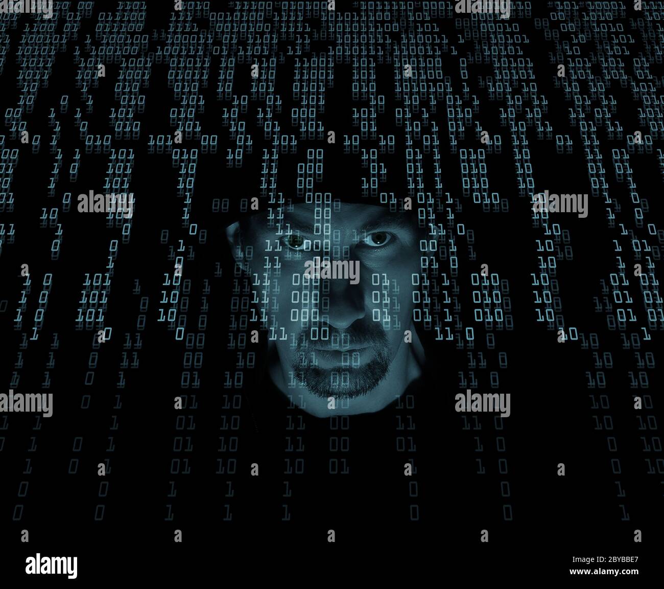 A man in a hood in a stream of binary code. Cyber criminal and data stream with light blue filter background. Stock Photo