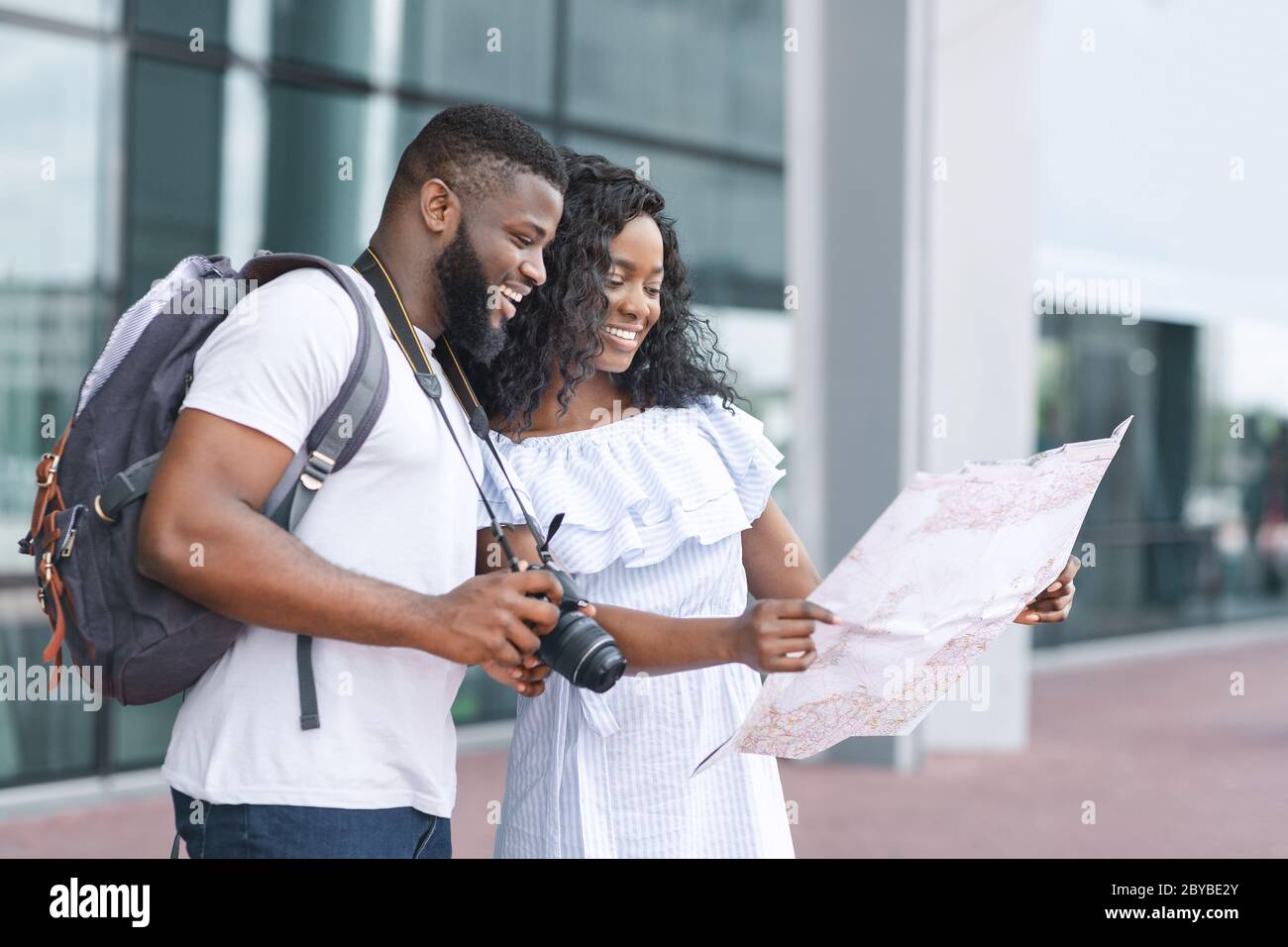 Couple of black tourists checking city map, planning route near airport Stock Photo