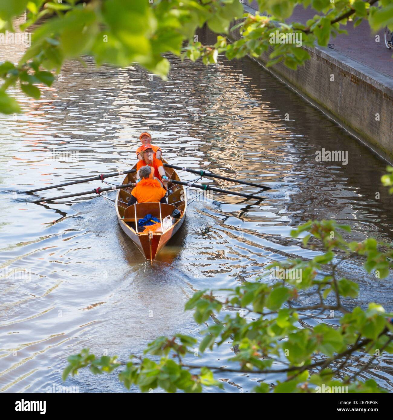 Typical orange dressed dutchmen in a boat on Queen's Day Stock Photo