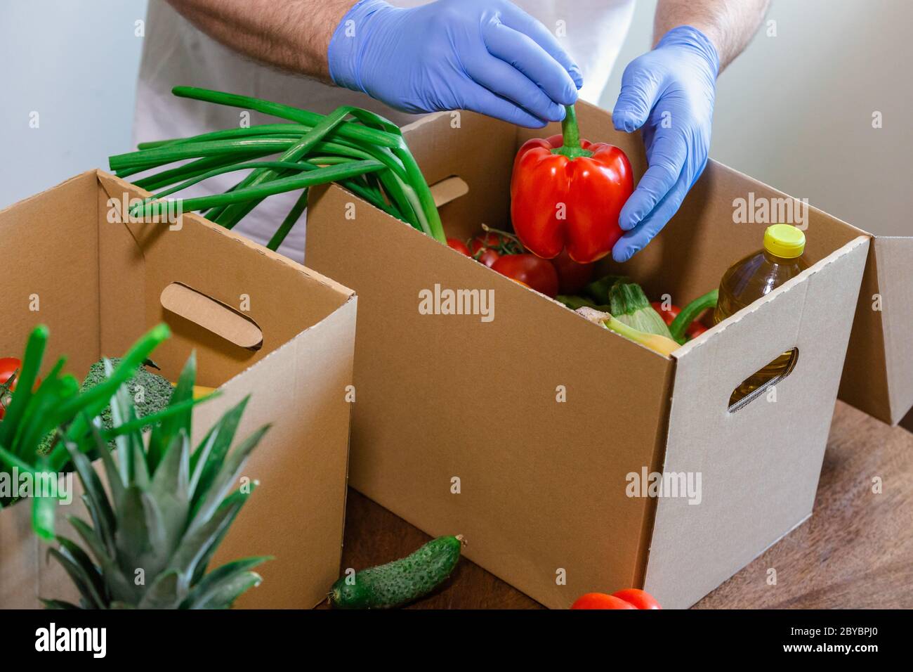 Coronavirus Relief Funds and Donations. Volunteer in the Protective Medical Mask and hand Gloves Putting Food In Donation Box. Charity donations. Stock Photo