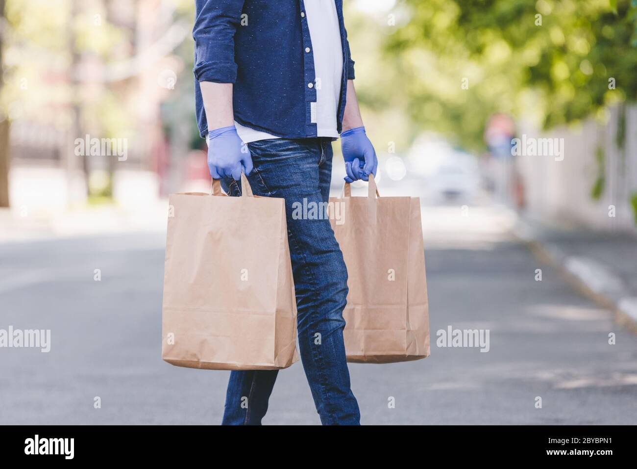 Courier  with medical gloves delivers takeaway food.        Delivery service under quarantine, disease outbreak, coronavirus covid-19 pandemic conditi Stock Photo