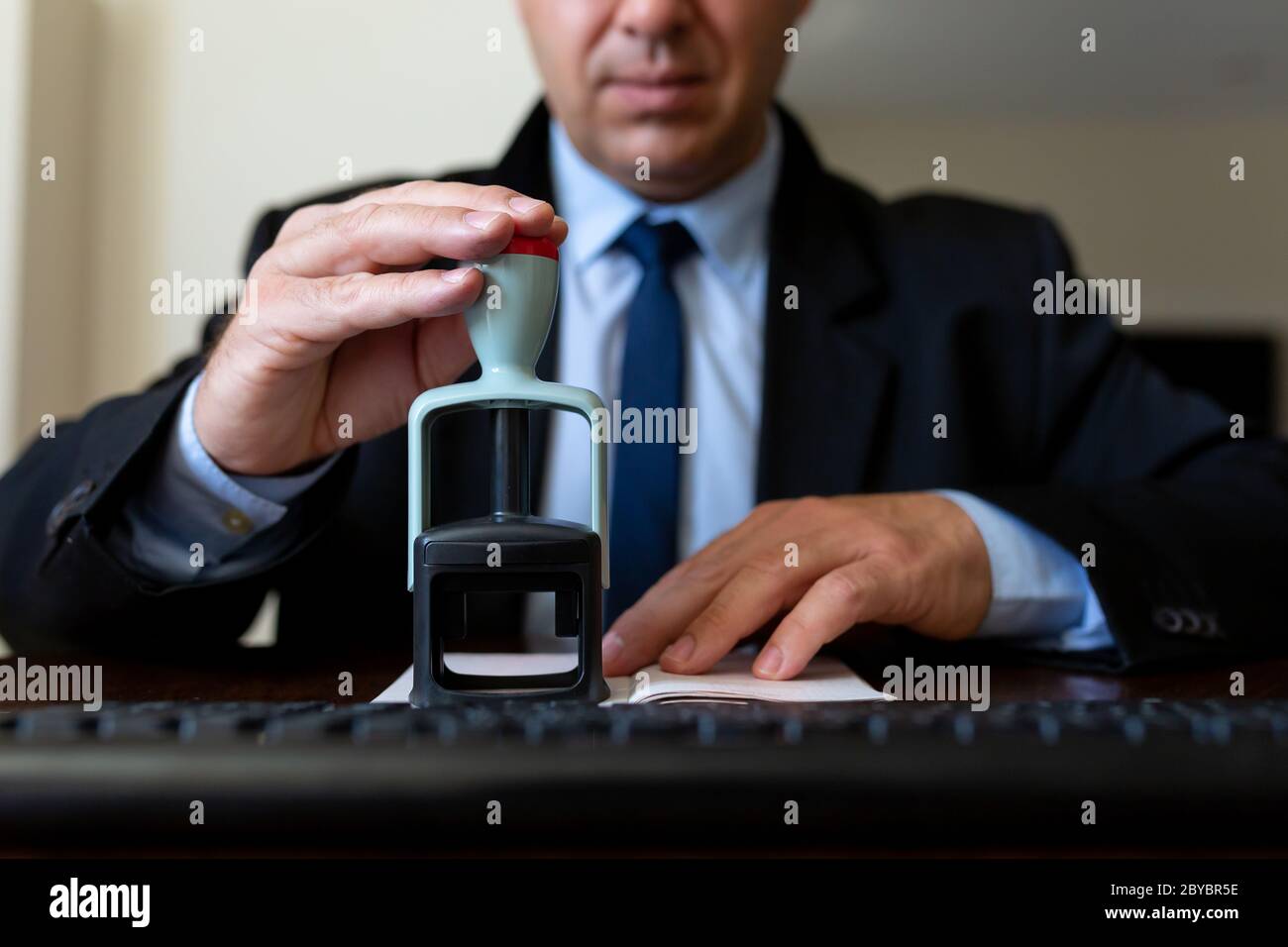 Close up. The airport employee checks the passports of passengers boarding the aircraft. He looks at his passport and stamps it. Stock Photo