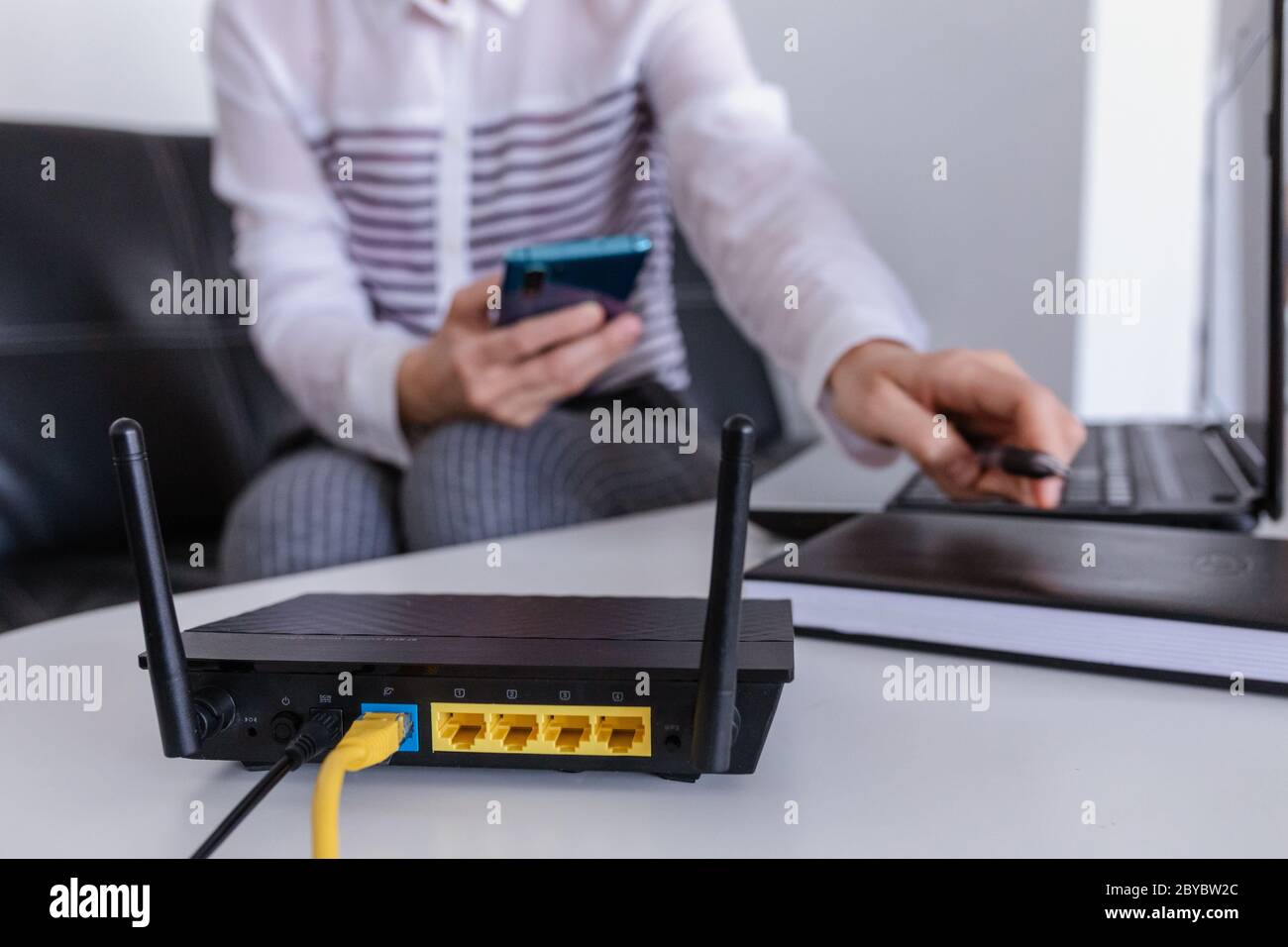 Wireless router and woman using a phone in office. router wireless broadband home laptop computer phone wifi concept Stock Photo