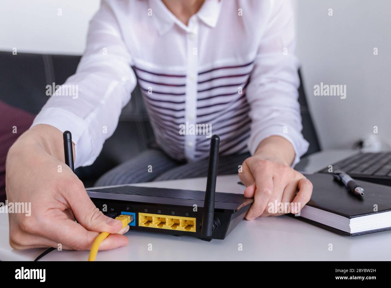 hand and lan network cable with people work on wireless router, Stock Photo