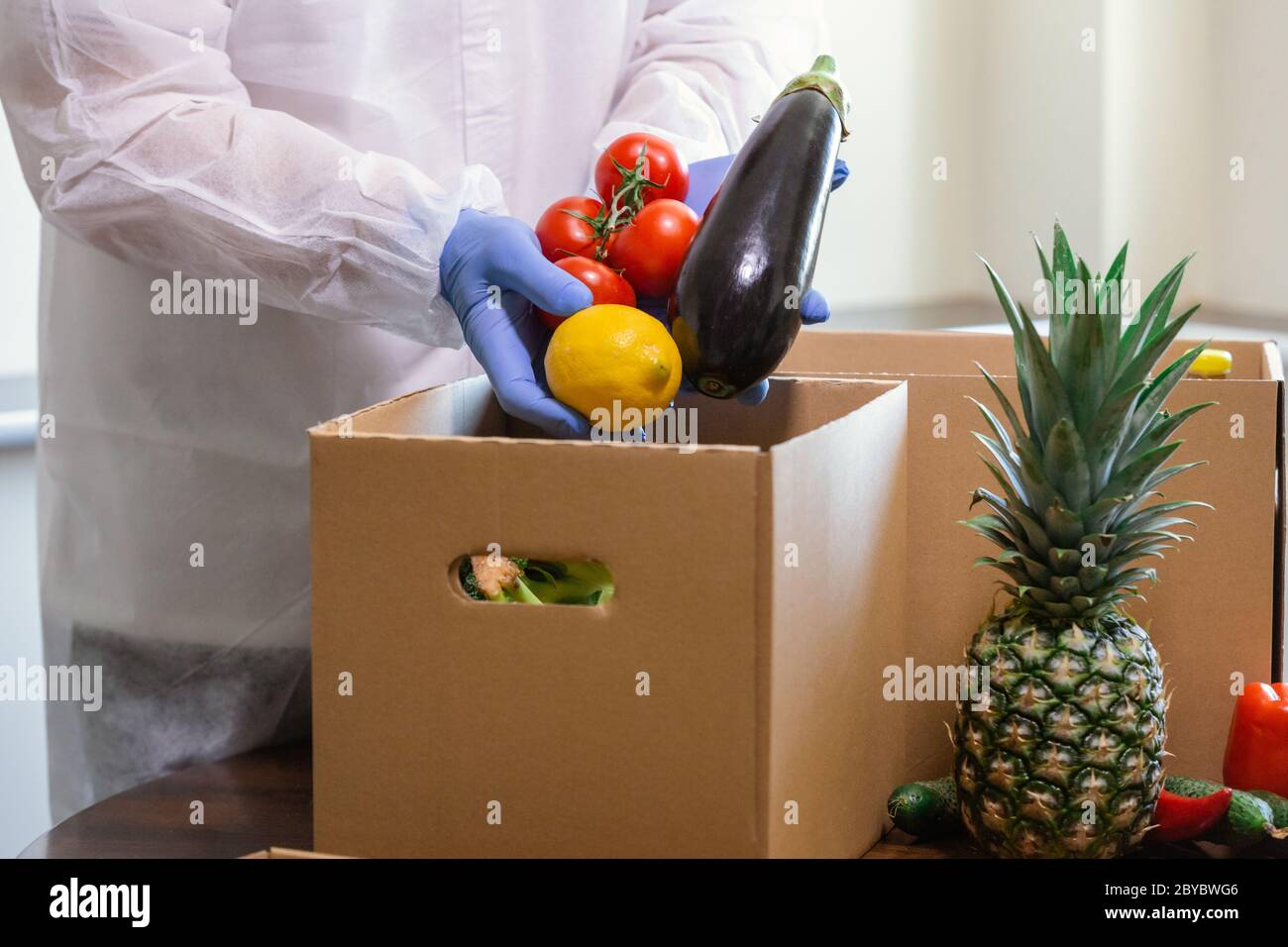 Coronavirus Relief Funds and Donations. Volunteer in the Protective Medical mask and hand Gloves Putting Food In Donation Box.       Charity donations Stock Photo