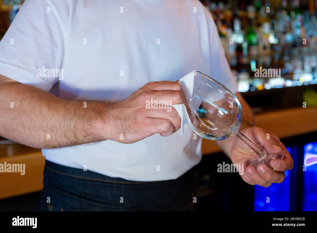 Bartender at the Bar Cleaning a Glass. Stock Photo