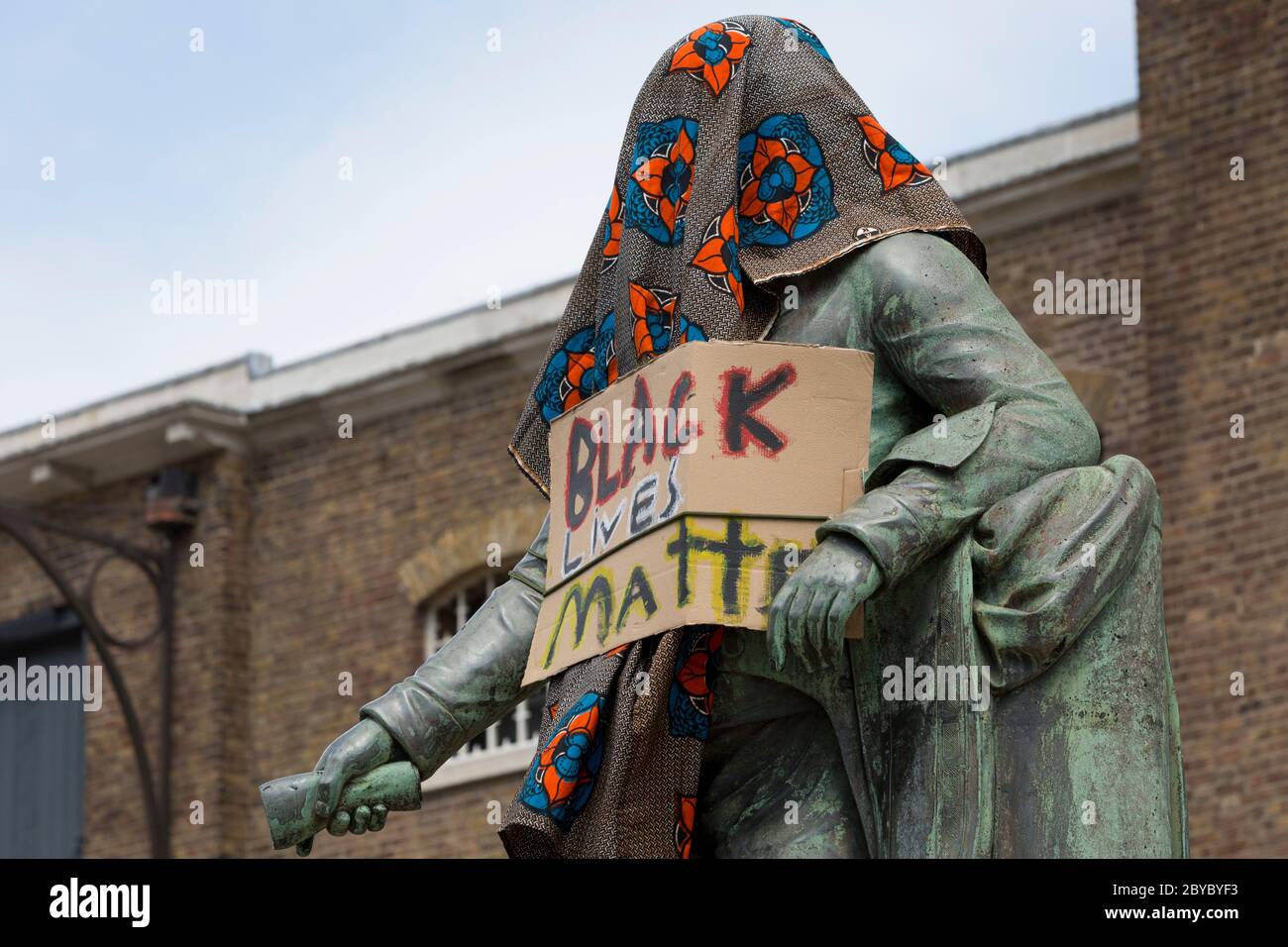 Hours before it was removed by the Canal and River Trust charity, the statue of slave merchant, Robert Milligan stands covered by Black Lives Matter activists outside the Museum of London's Docklands Museum on West India Quay, once the world's longest warehouse paid for by slavery profits, 9th June 2020, in London, England. In the aftermath of the George Floyd protests in the US and UK Black Lives Matter groups, who are calling for the removal of statues and street names with links to the slave trade, Milligan's and other statues of British slavery profiteers, have become a focus of protest. Stock Photo