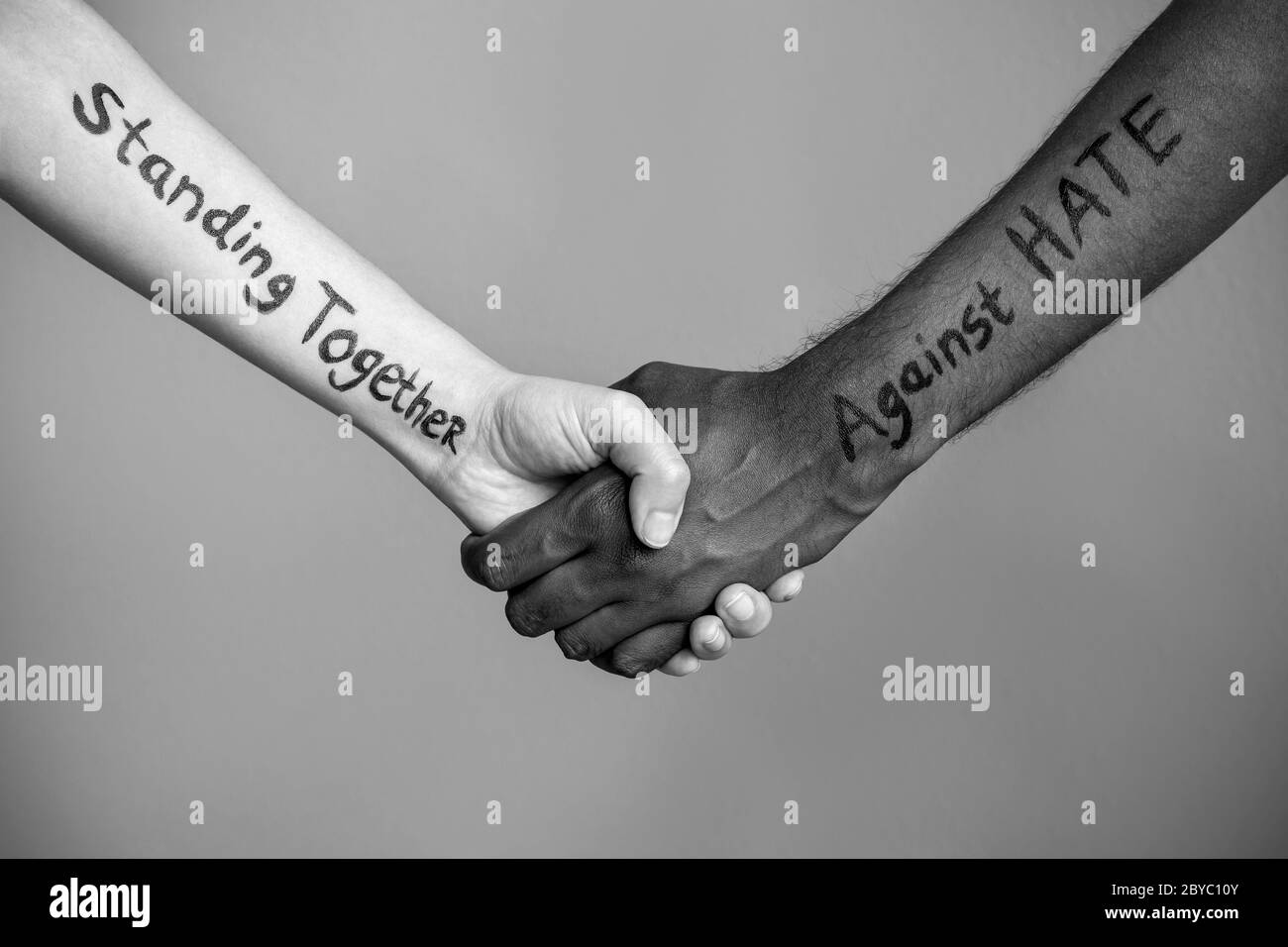 Handshake between black and white human woman and male hands with message text Standing Together against HATE. Concept of Black Lives Matter protest Stock Photo
