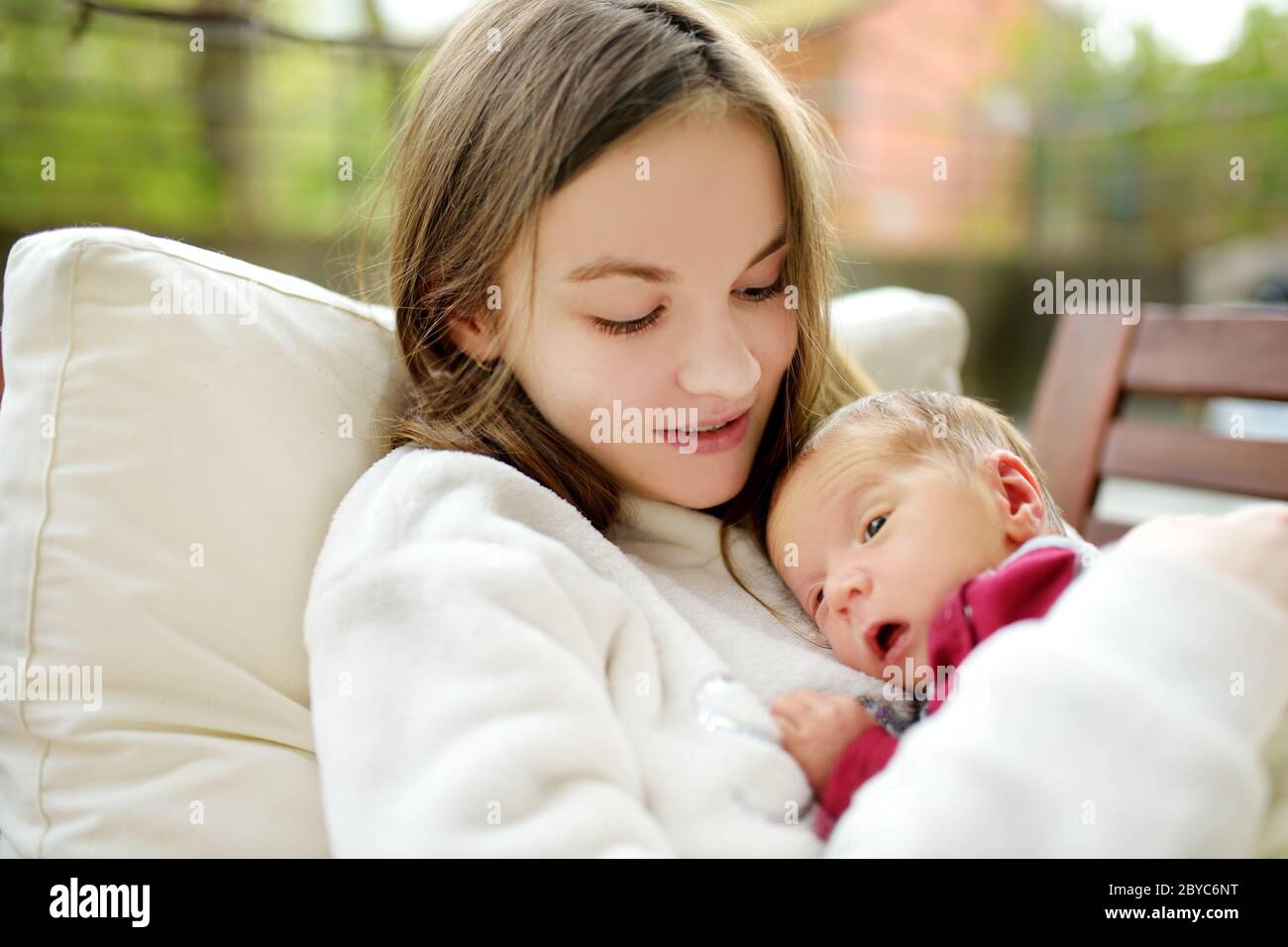Cute big sister admiring her newborn brother. Adorable teenage girl