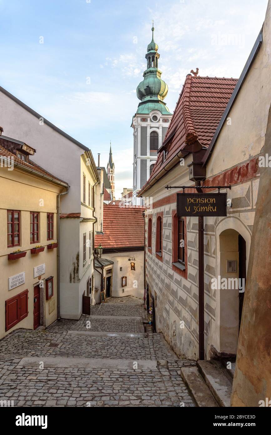 A narrow street consisting of cobblestone steps with the Baroque bell tower of the Saint Jost Church Stock Photo