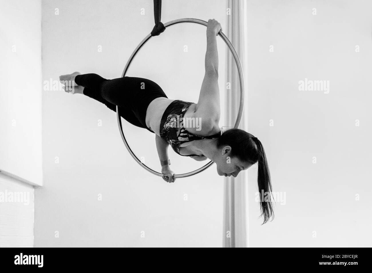 A Colombian aerial dancer performs a balance trick on aerial hoop during a training session in a gym in Medellín, Colombia. Stock Photo