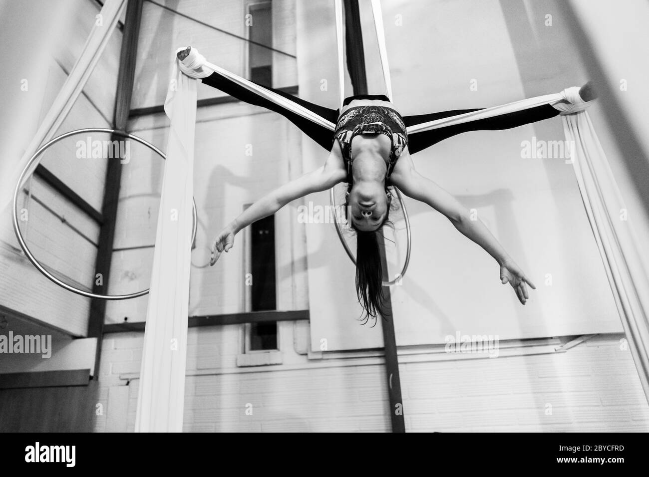 A Colombian aerial dancer performs a balance trick on aerial silks during a training session in a gym in Medellín, Colombia. Stock Photo