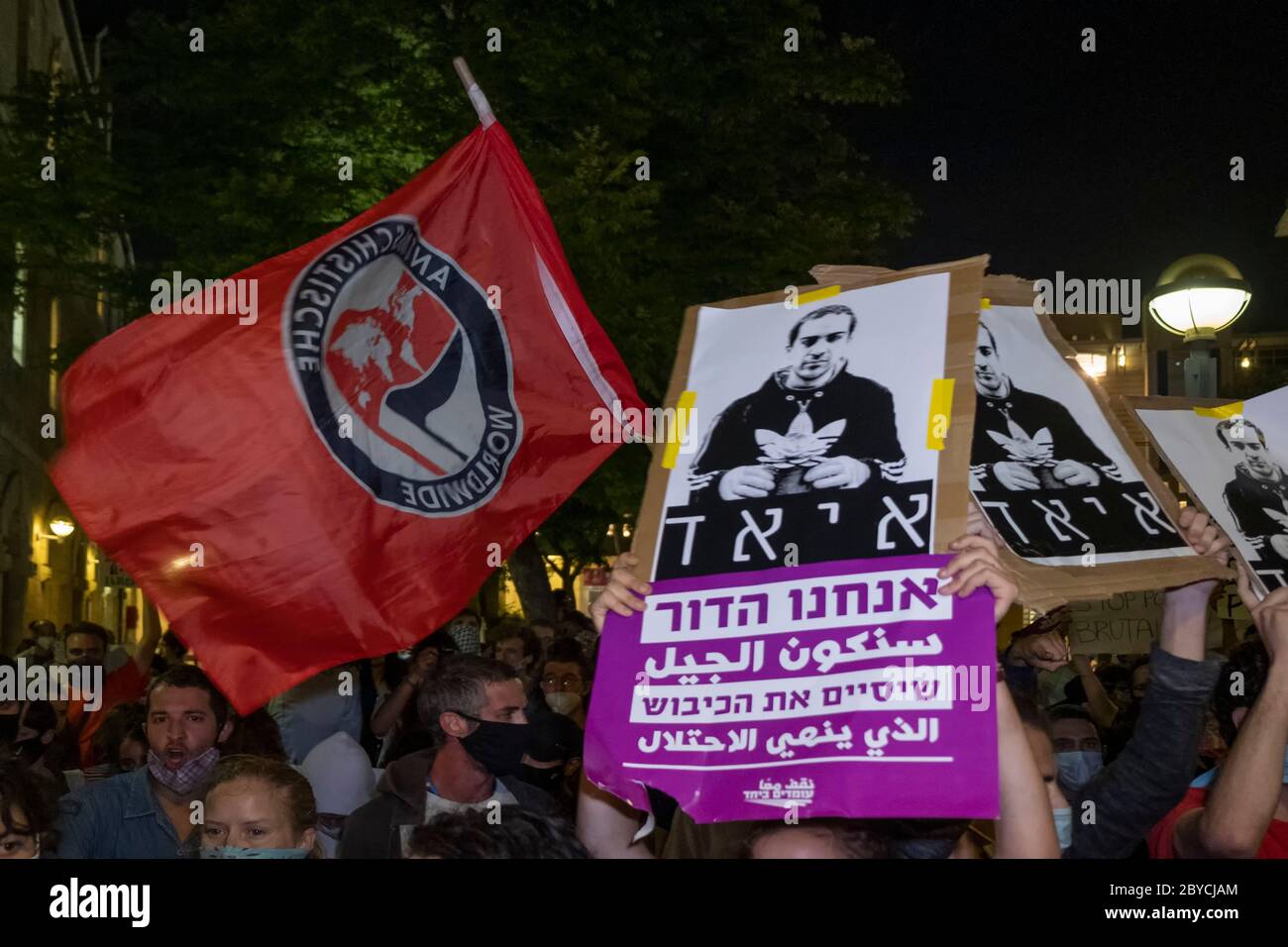 Jerusalem, Israel. 9th June, 2020. Left-wing activists wave the flag of anti-fascist political movement Antifa and placards bearing the image of Iyad Hallak during a protest in Jerusalem on June 9, 2020 against the killing of Iyad Hallak, a disabled Palestinian man shot dead by Israeli police as well of the killing of unarmed African-American George Floyd. Credit: Eddie Gerald/Alamy Live News Stock Photo