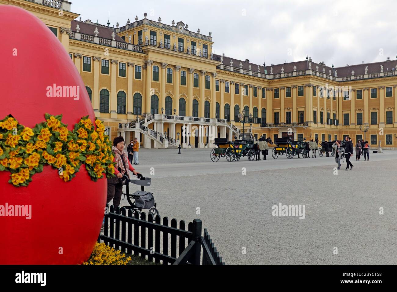 Outside Schonbrunn Palace in Vienna, Austria are horse-drawn carriages and a large Easter egg planter celebrating the spring holiday. Stock Photo