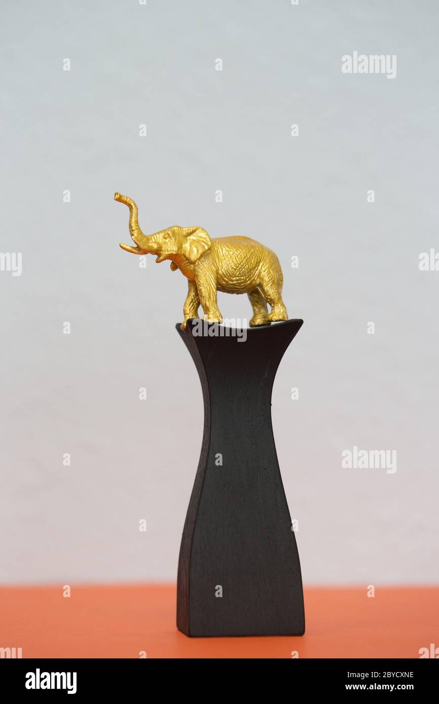 A gold elephant figurine on a pedestal. Stock Photo