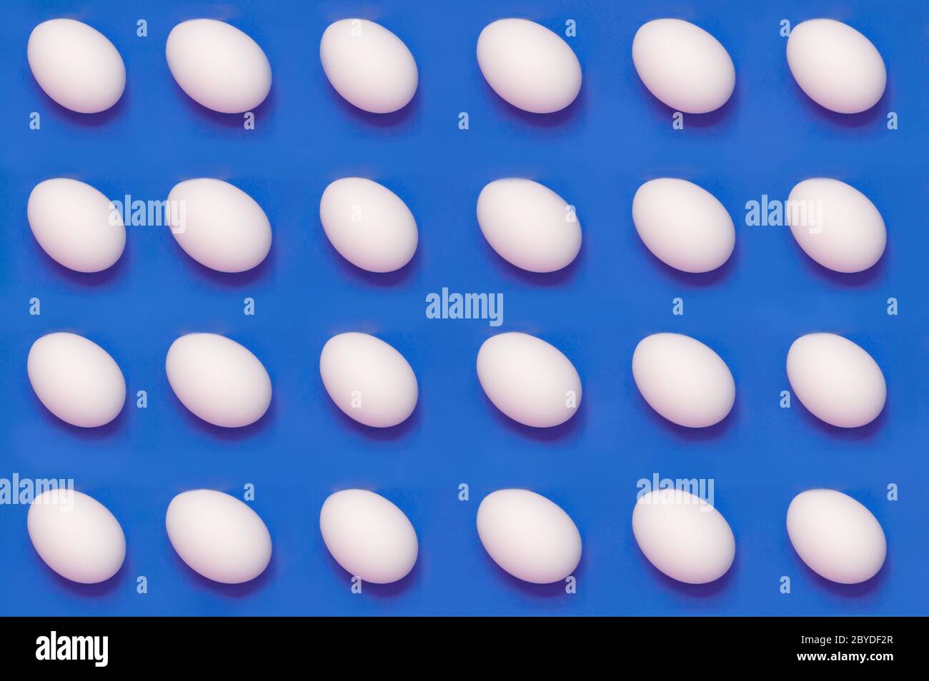 White eggs arranged on solid color background Stock Photo