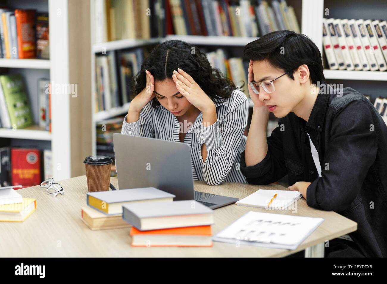 Stressed students preparing for examination in library Stock Photo