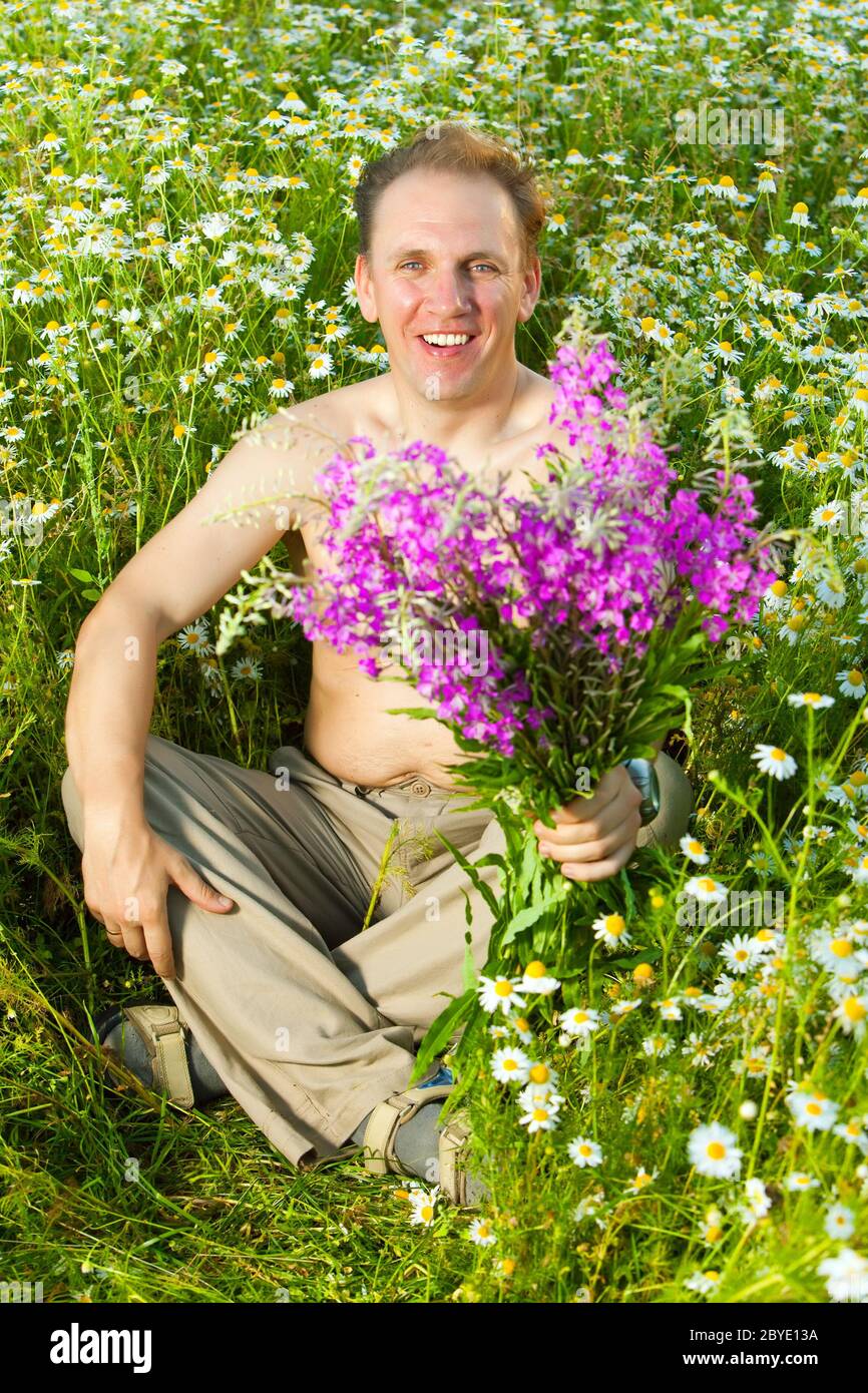 The man in the field of camomiles gives a bouquet Stock Photo