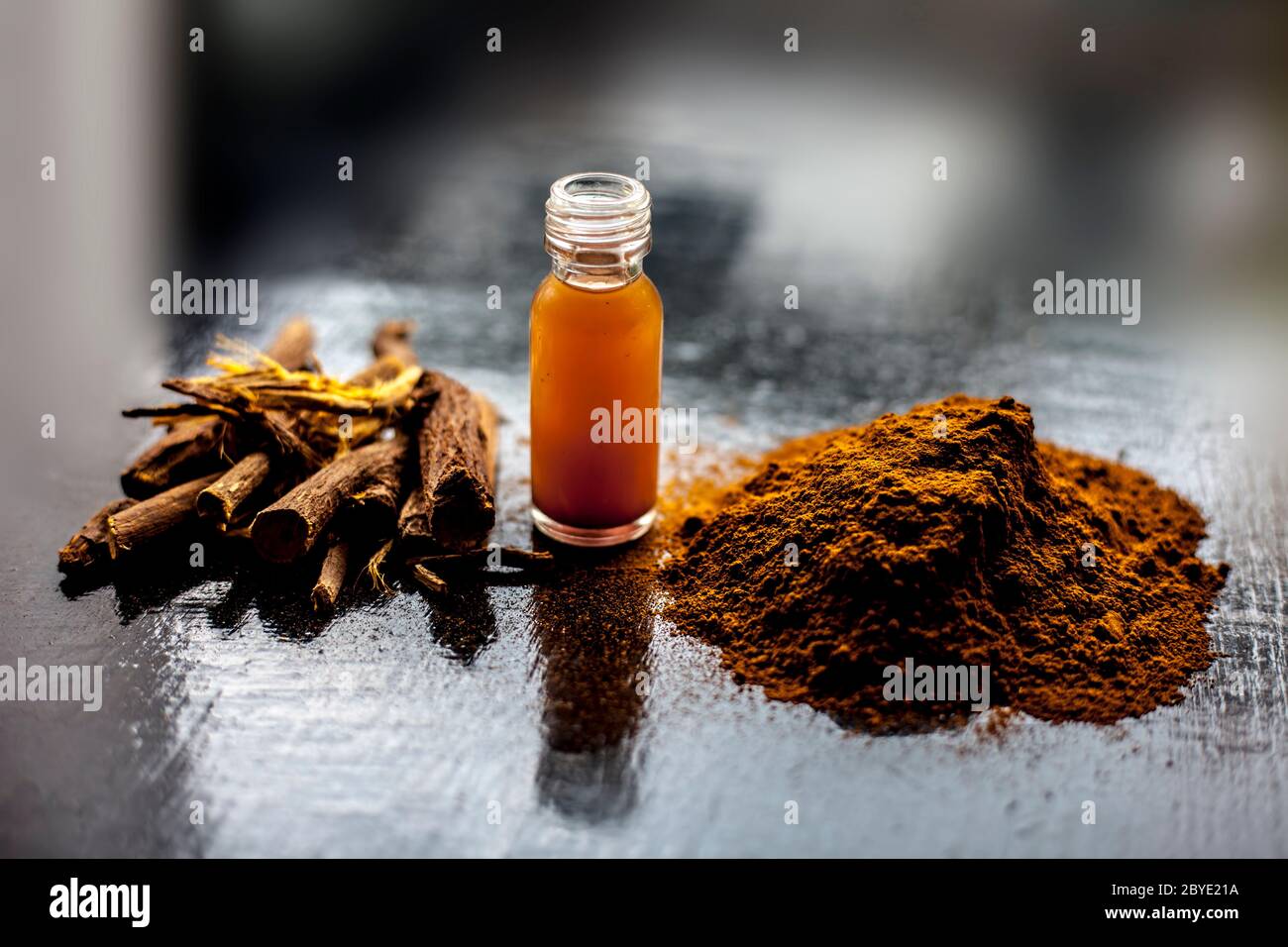 Shot of Rheum emodi or Revand Chini along with its extracted root essence and raw powder on a black glossy surface. Stock Photo