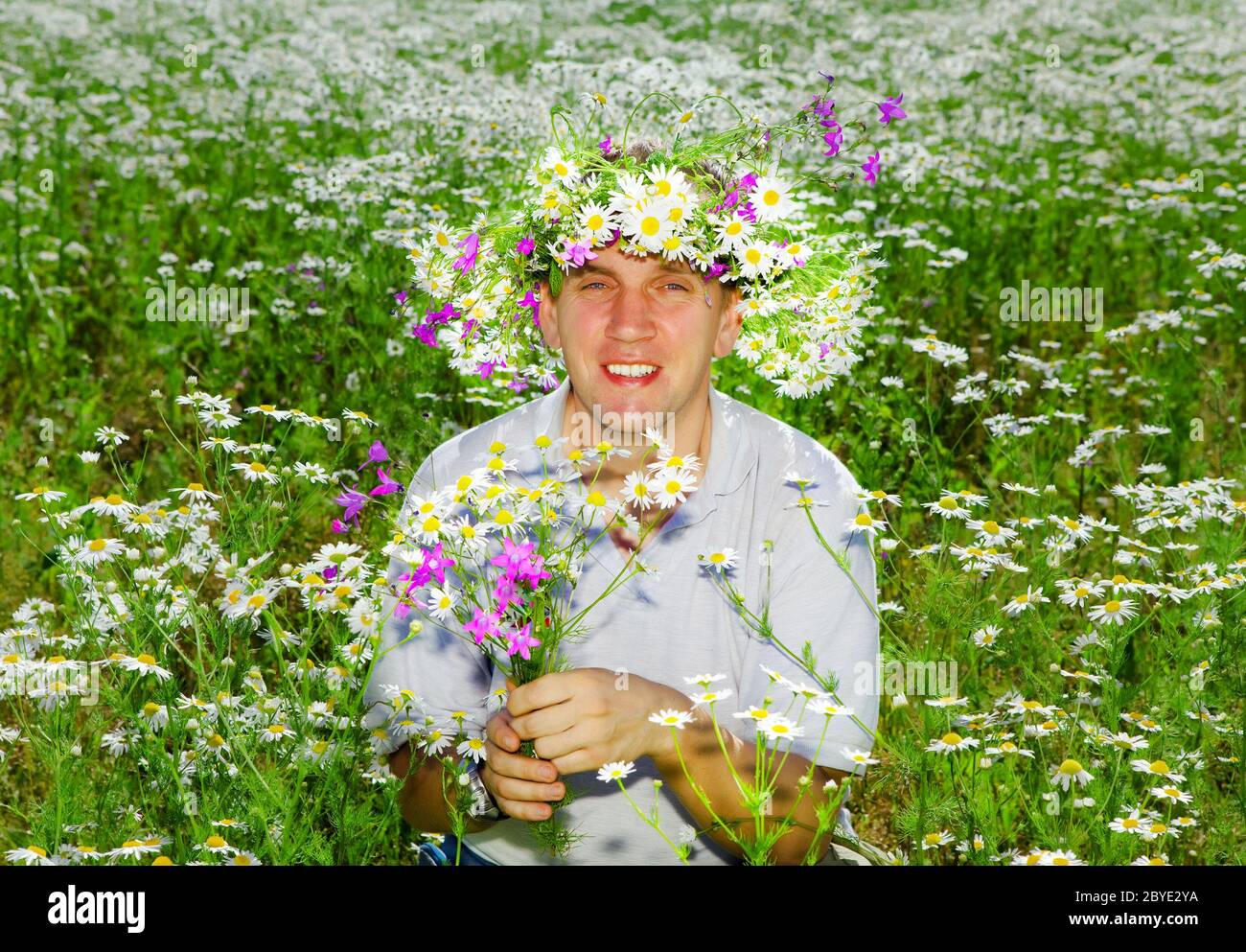The smiling man in a wreath from wild flowers in Stock Photo
