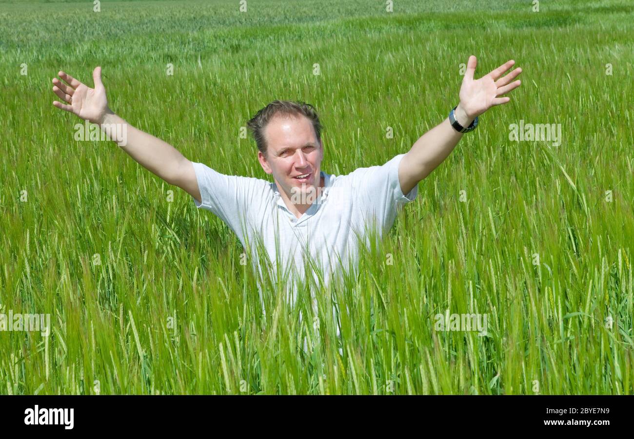 The happy young man in the field of green ear Stock Photo
