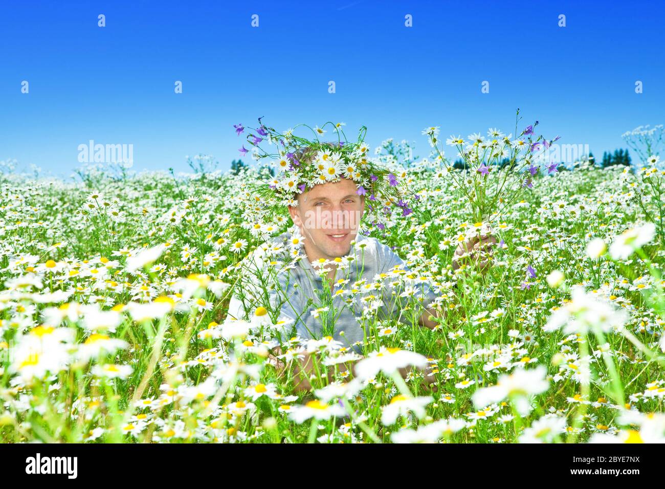 man in a wreath from wild flowers in the field Stock Photo